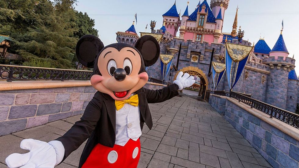 Mickey Mouse greets visitors in front of a castle at Disneyland