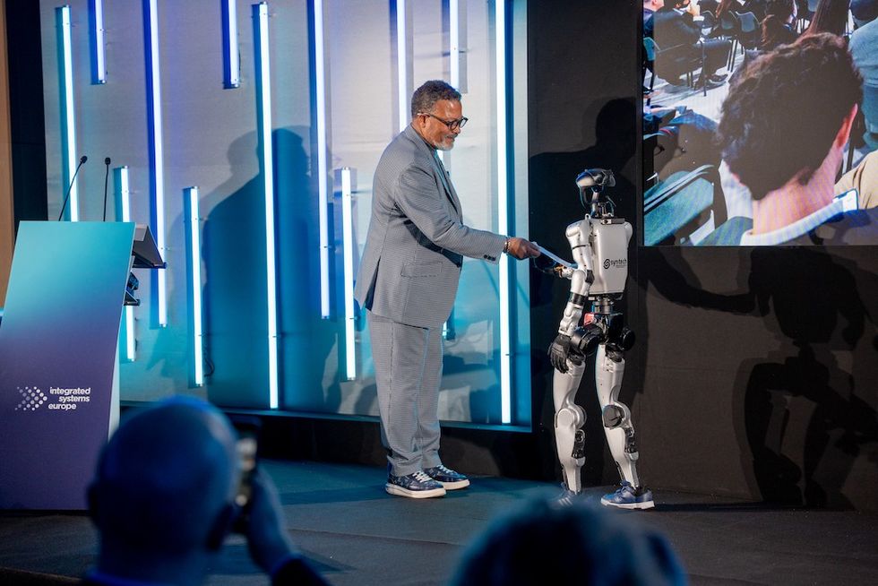 Mike Blackman shakes hands with a humanoid robot on stage at ISE 202.