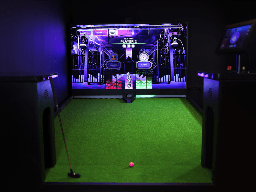 Mini-golf simulator with neon graphics and green turf.