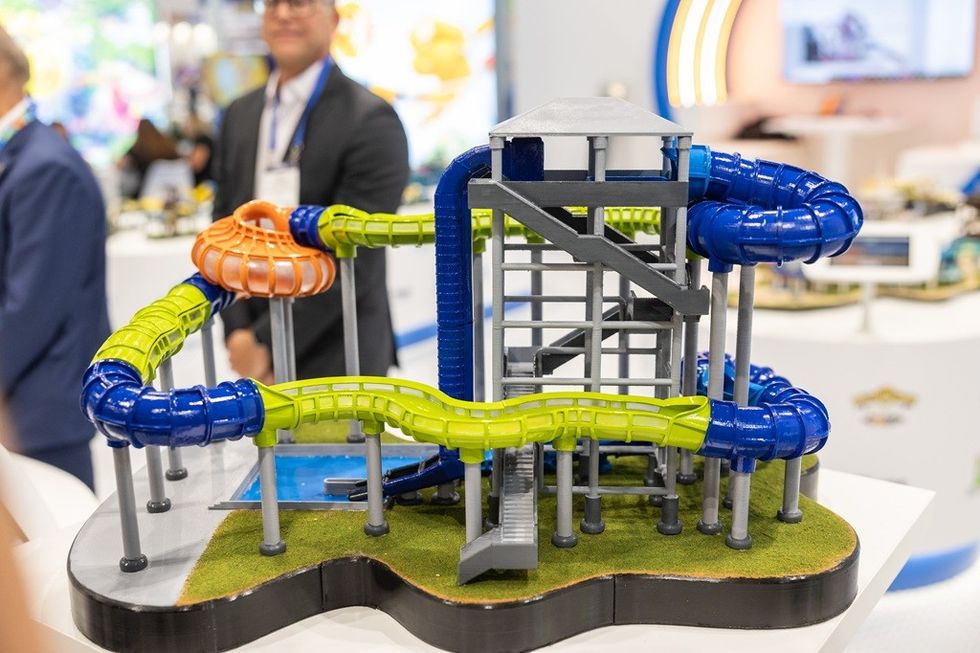 Miniature water slide model with blue and green tubes, displayed on a table.