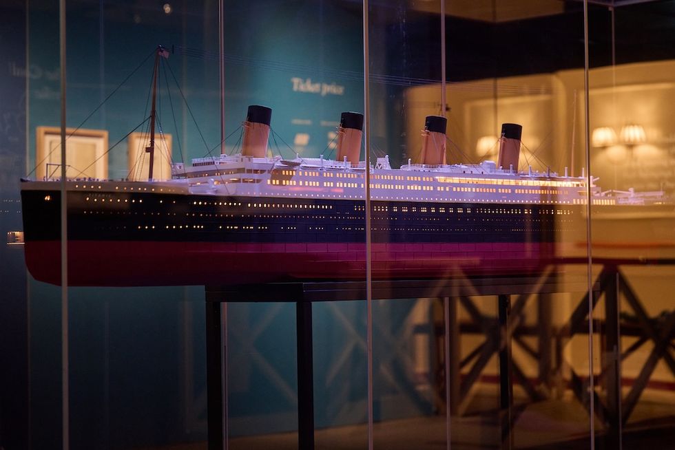 Model of a large ship with illuminated interior, displayed in a glass case.