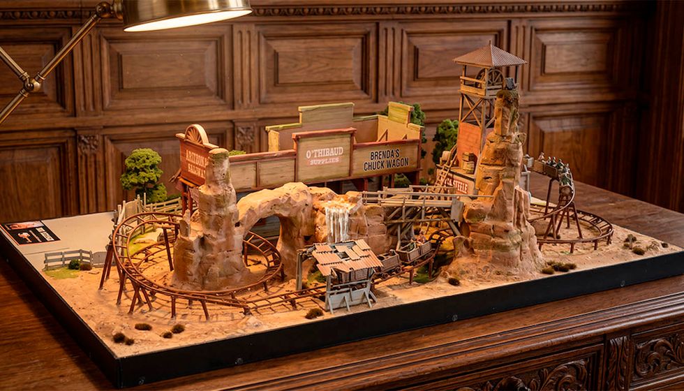 Model of a Wild West-themed roller coaster with desert scenery on a wooden table.