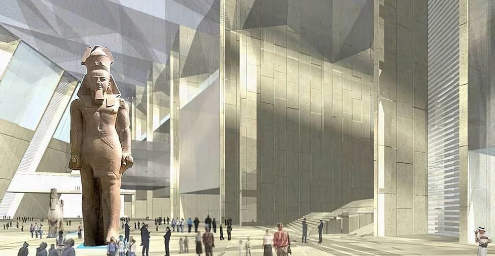 Modern atrium with large ancient Egyptian statue and people around at the Grand Egyptian Museum.