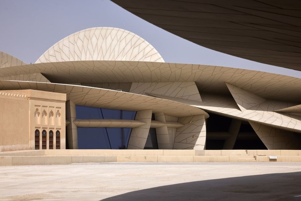 Modern building at National Museum of Qatar with curved, geometric shapes under a clear sky.