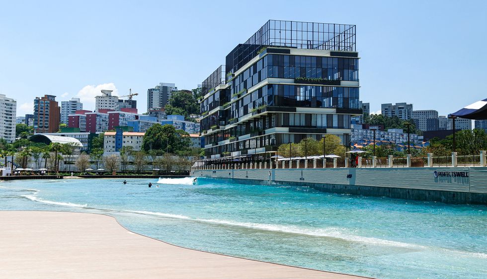 Modern building by a pool, with brightly colored cityscape in the background.