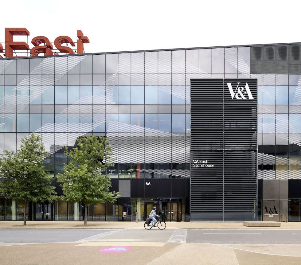 Modern building facade with "V&A East Storehouse" sign and a cyclist in front.