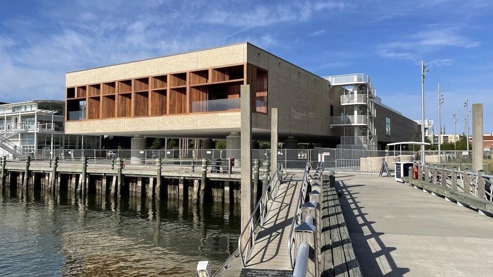 Modern building on waterfront with wooden accents, seen from a dock.