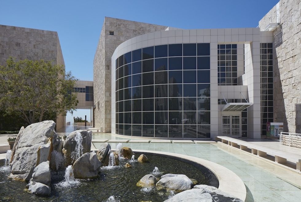 Modern building, The J. Paul Getty Center, with large glass windows, stone facade, and a water fountain in front.