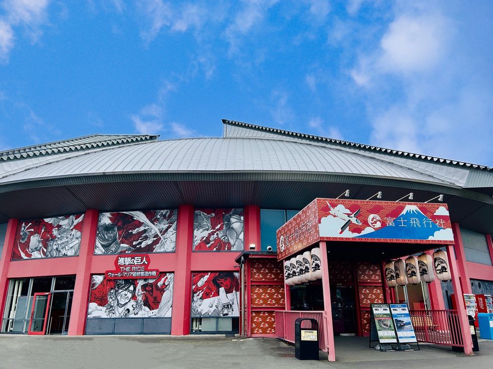 Modern building with anime artwork on walls, featuring a red entrance and lantern decorations.