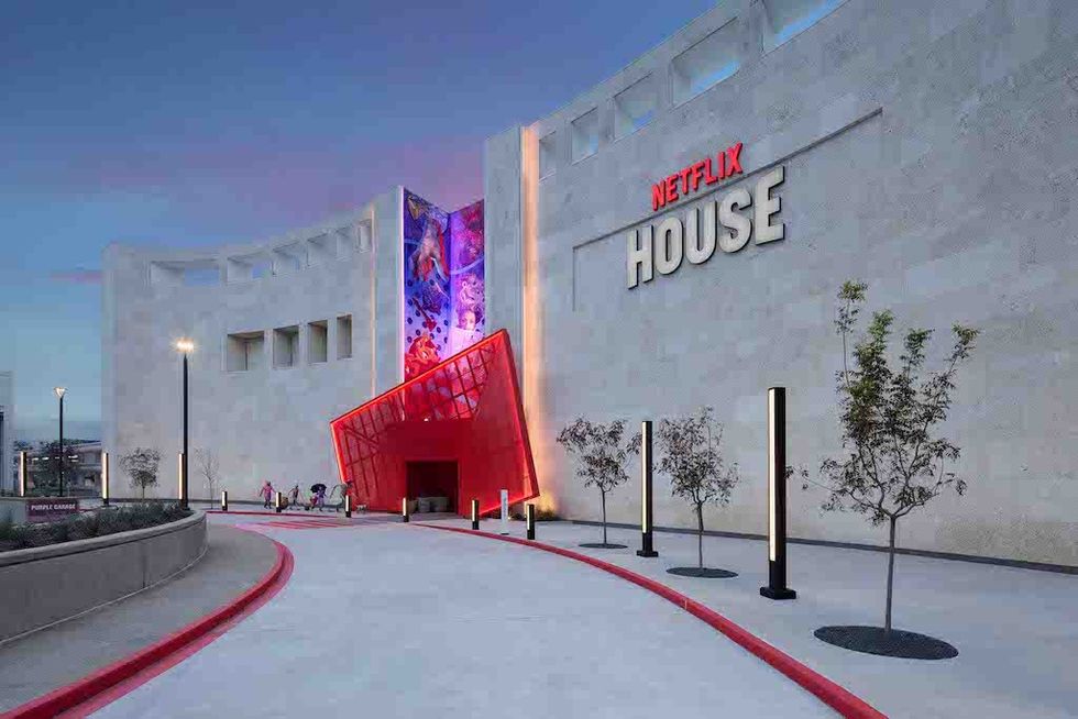 Modern building with "Netflix House" sign and a vibrant, red entrance under dusk sky.