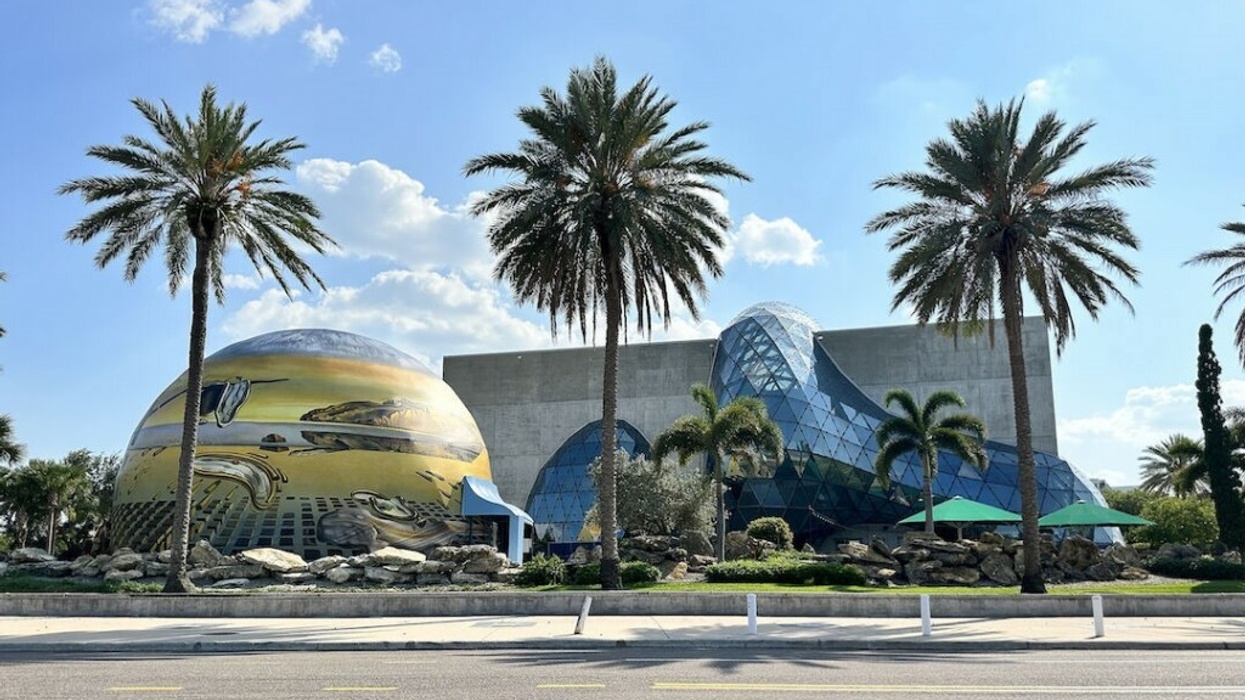 Modern building with palm trees, featuring dome art and a glass geometric structure.