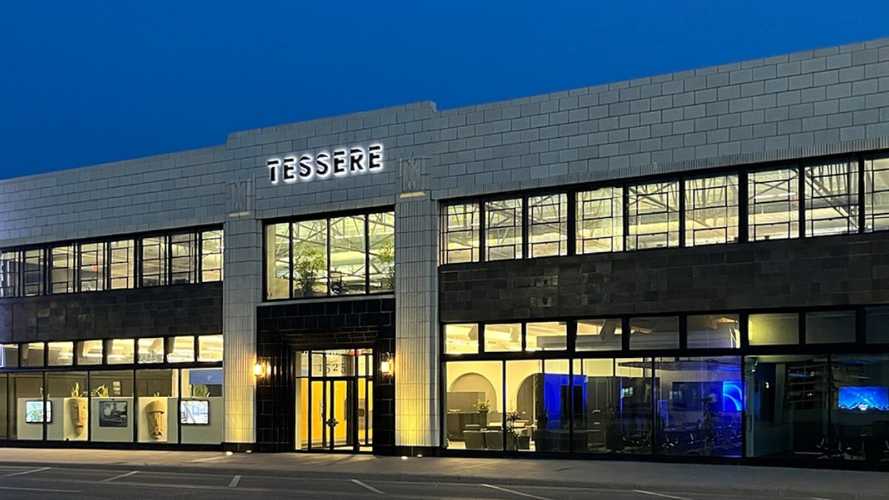 Modern building with "TESSERE" sign, well-lit at night, features large windows and blue lighting.