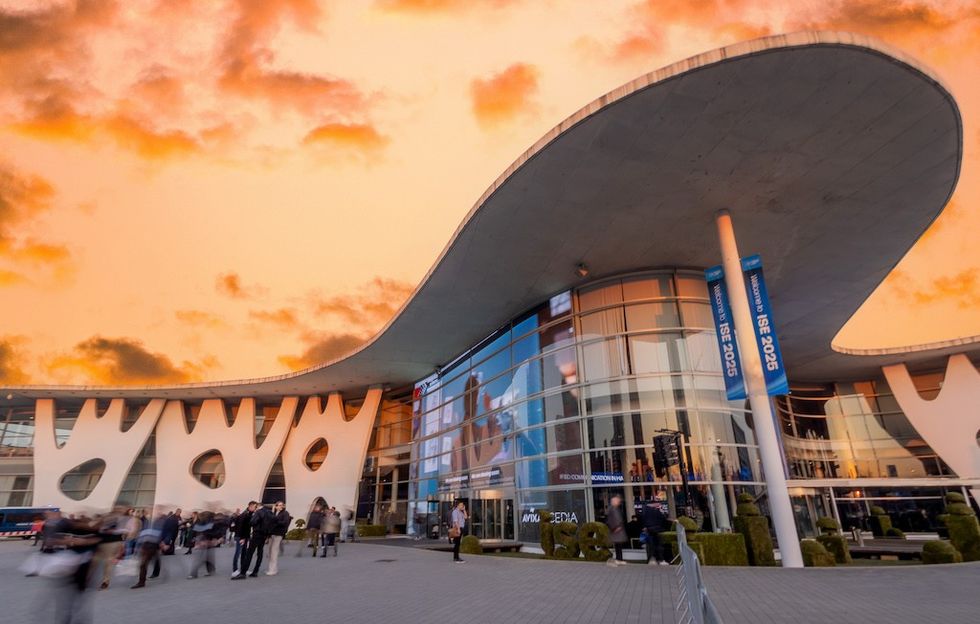 Modern building with unique architecture at sunset, people gathered outside.