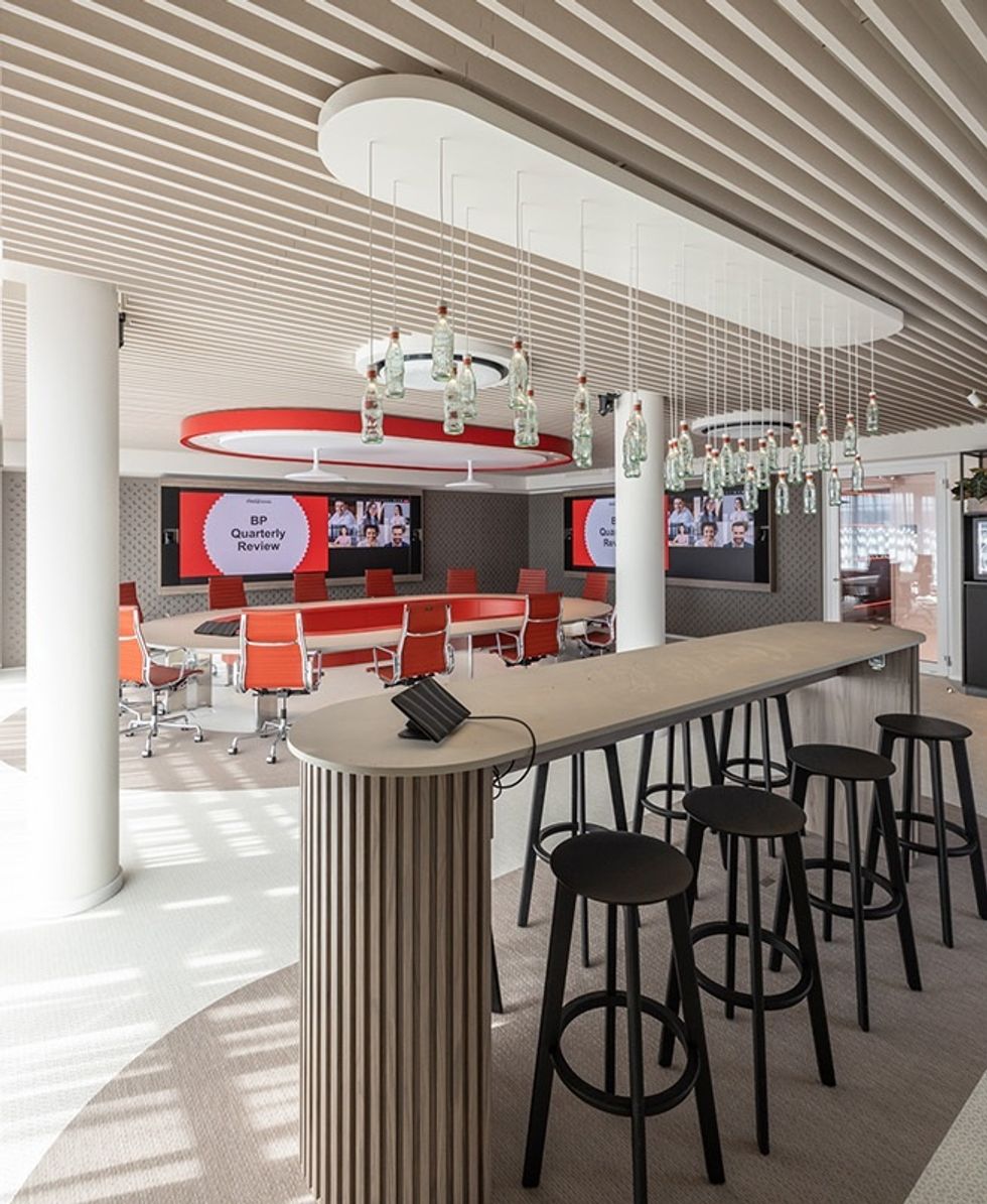 Modern conference room at THE 6TH FLOOR with orange chairs, hanging bottles, and bar stools.