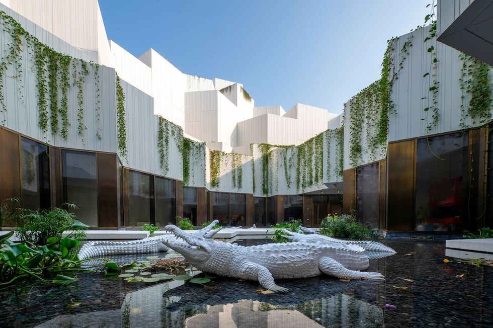 Modern courtyard with white alligator sculptures and hanging greenery.