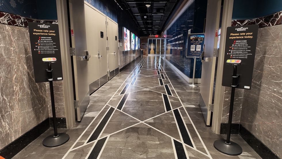 Modern hallway with geometric floor design and feedback stations on both sides.