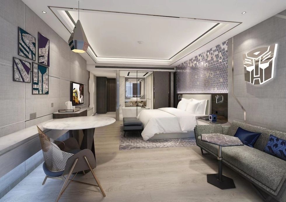 Modern hotel room with Transformers decor, featuring a bed, couch, and wall art.