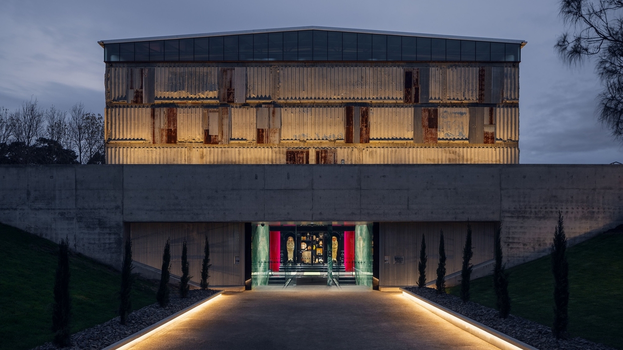 Modern illuminated building at Mona with a textured facade at dusk, featuring a lit path to entrance.