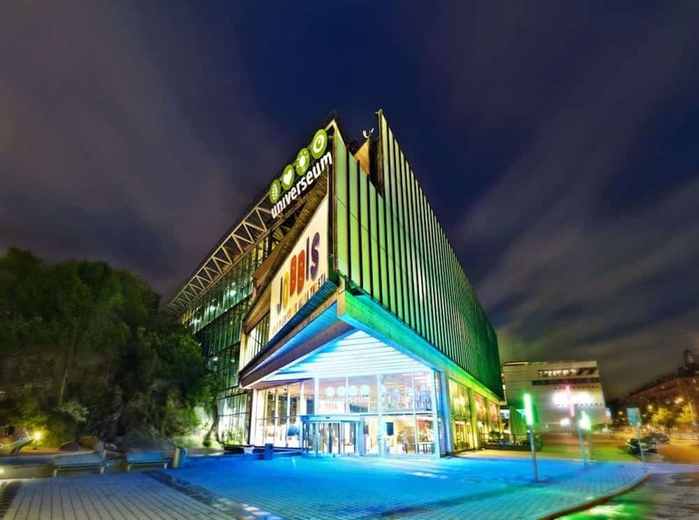 Modern, illuminated building at night with "universum" sign.