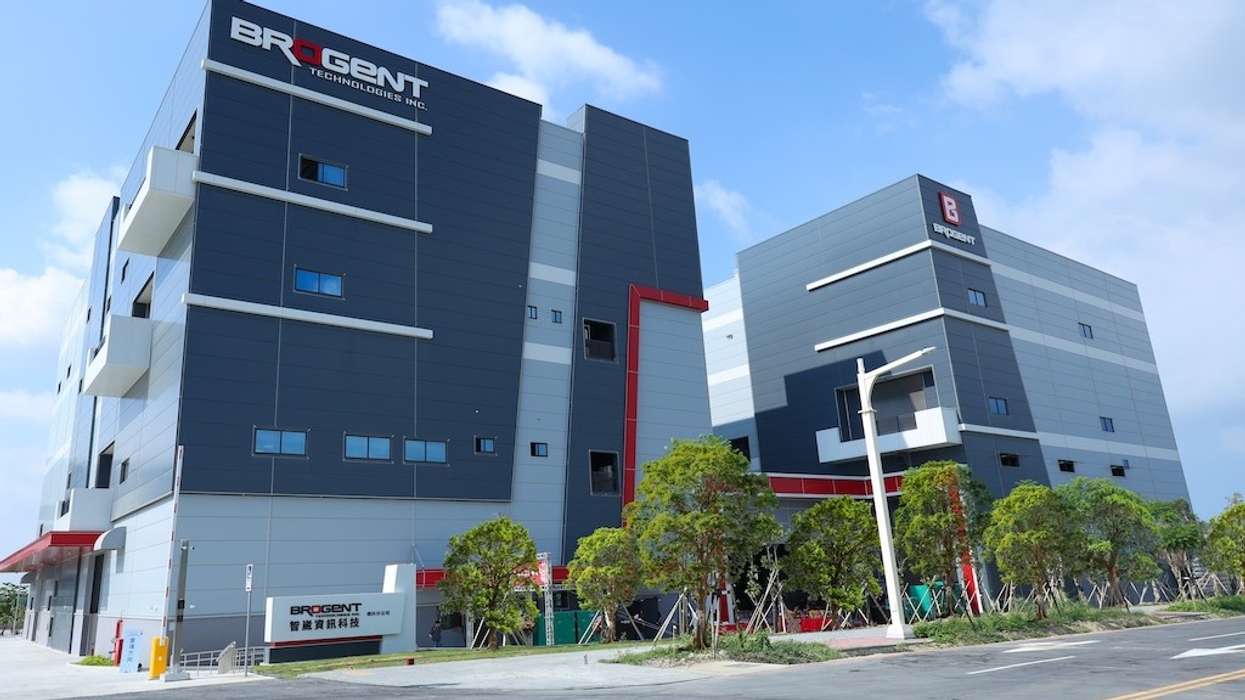 Modern industrial building with gray facade and Brogent company logo, surrounded by trees and road.