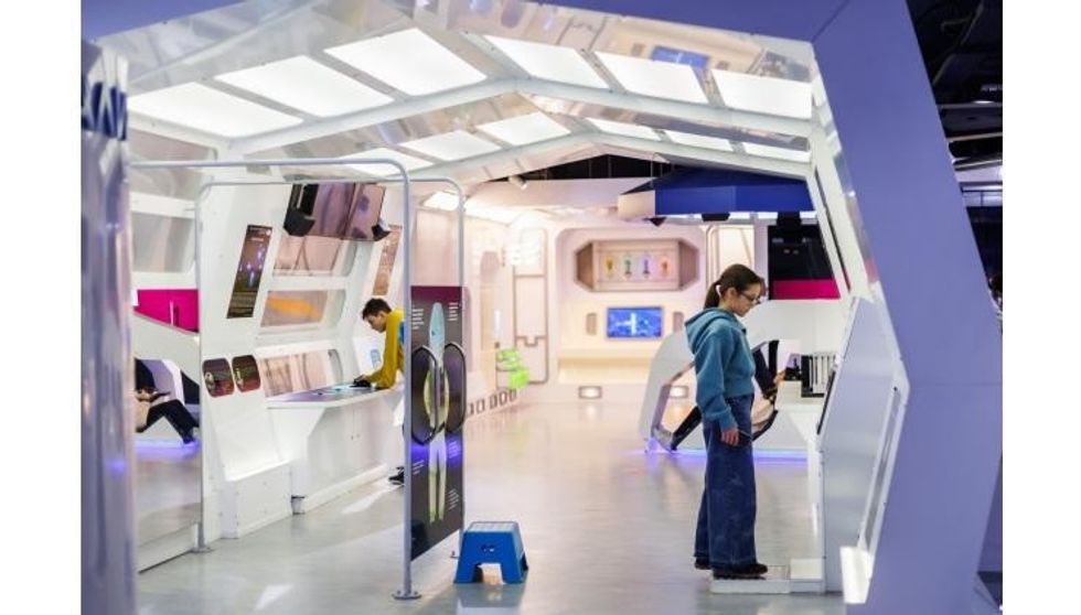 Modern interactive exhibit with people exploring digital displays in a brightly lit space at Muzeiko children's museum.