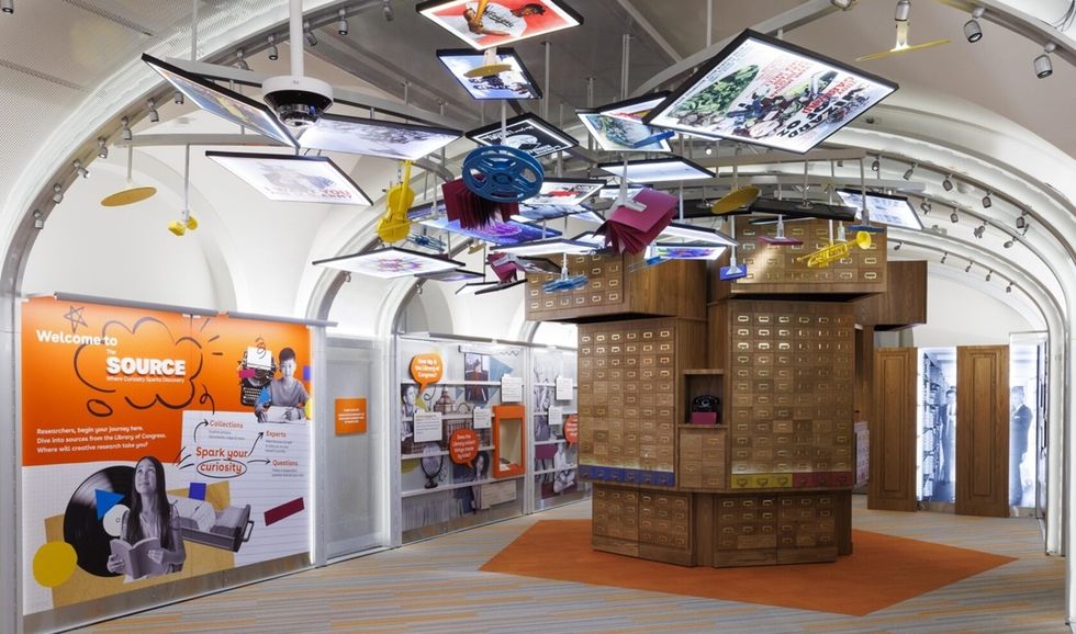 Modern library exhibit with suspended displays and vintage card catalog drawers.