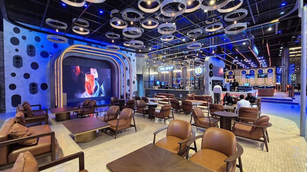 Modern lounge at BOLTS with stylish seating, large screen, and ambient blue lighting.