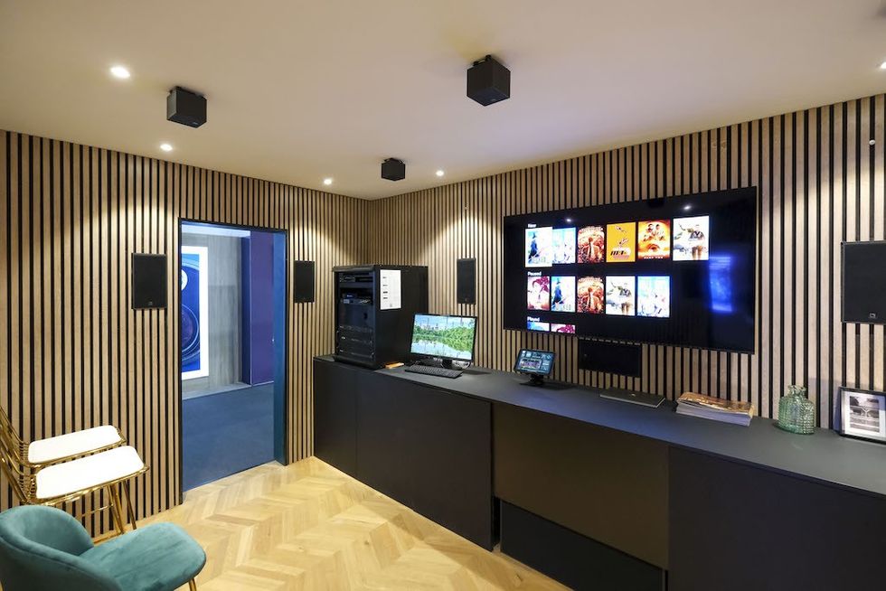 Modern media room with wood panel walls, large screen, and sound system.