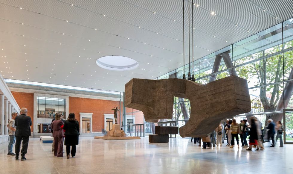Modern museum lobby with large sculpture, people observing.