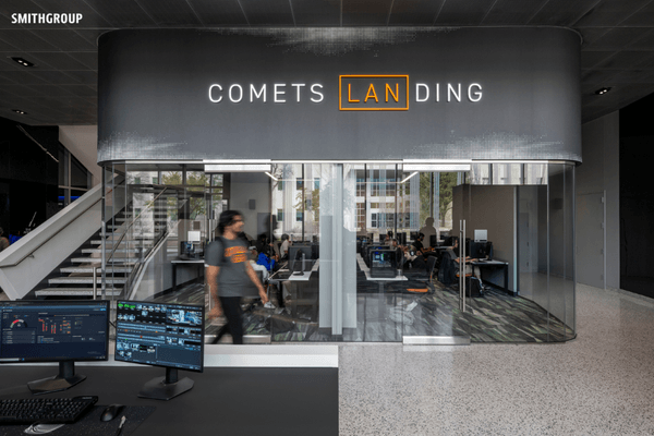 Modern office space with glass walls, labeled "Comets Landing," features computer workstations.