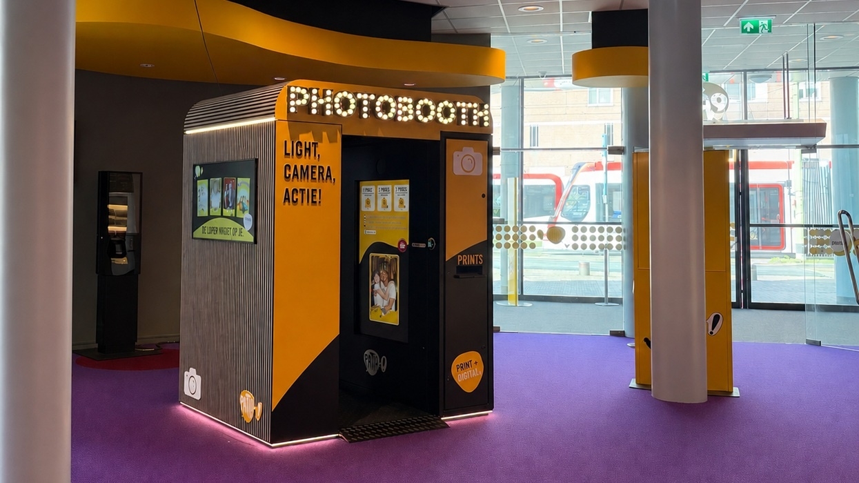 Modern photobooth with illuminated sign in a bright, open space.