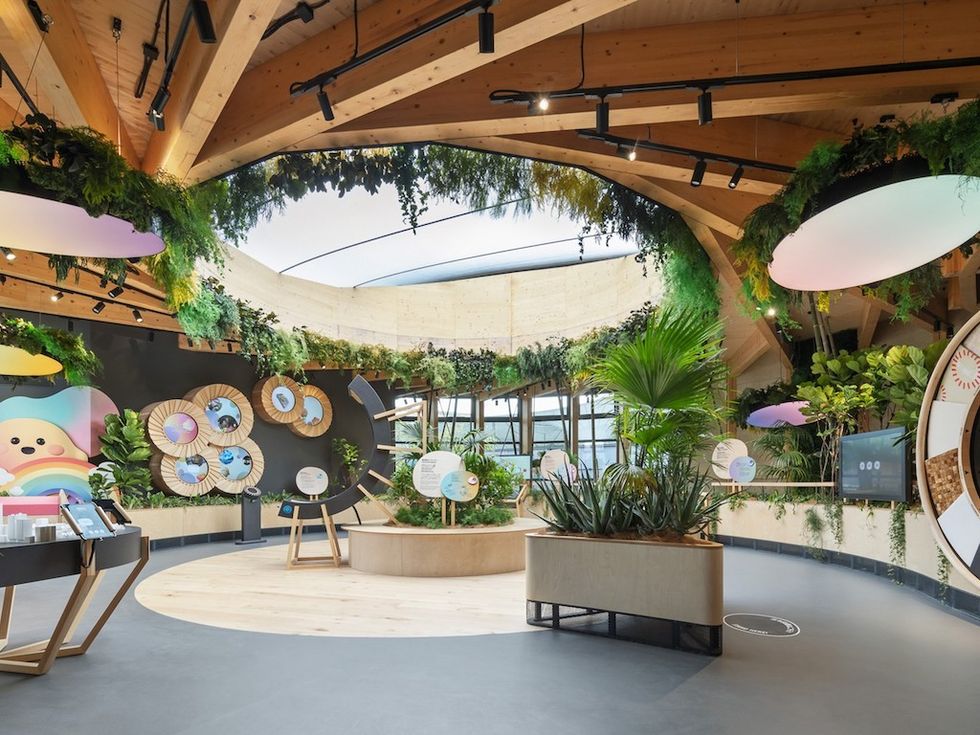 Modern, plant-filled room with wooden beams and colorful wall decorations.
