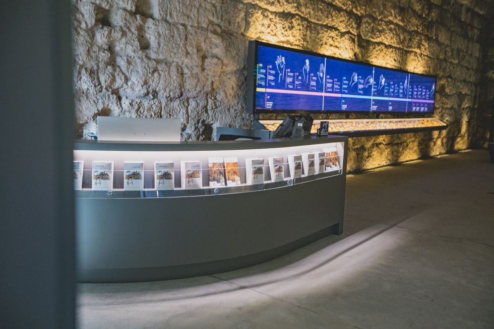 Modern reception desk with brochures, illuminated in a stone-walled room.