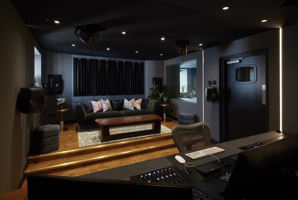 Modern sound mixing studio at Factory Immersive with a sofa, equipment, and dim lighting.
