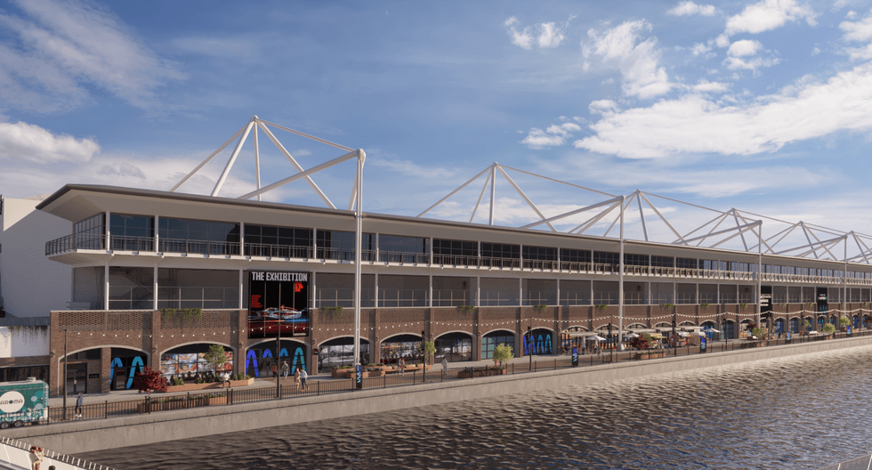 Modern waterfront building with glass facade and outdoor seating under a blue sky called Immerse LDN