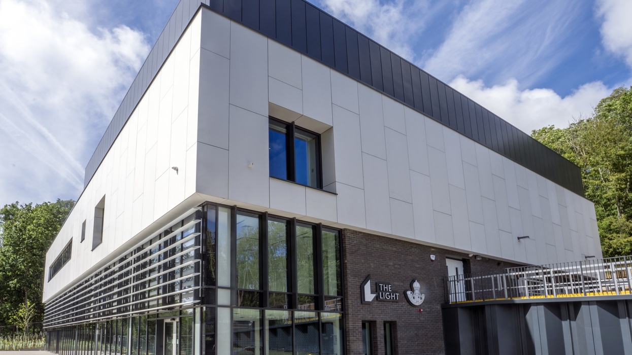 Modern white building with glass windows and "The Light" signage, under a blue sky.