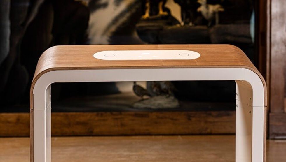 Modern wooden side table with curved edges in dimly lit room.
