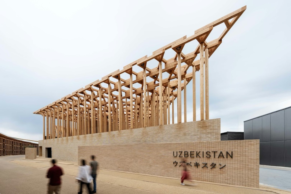 Modern wooden structure of Uzbekistan Pavilion with people walking in front.