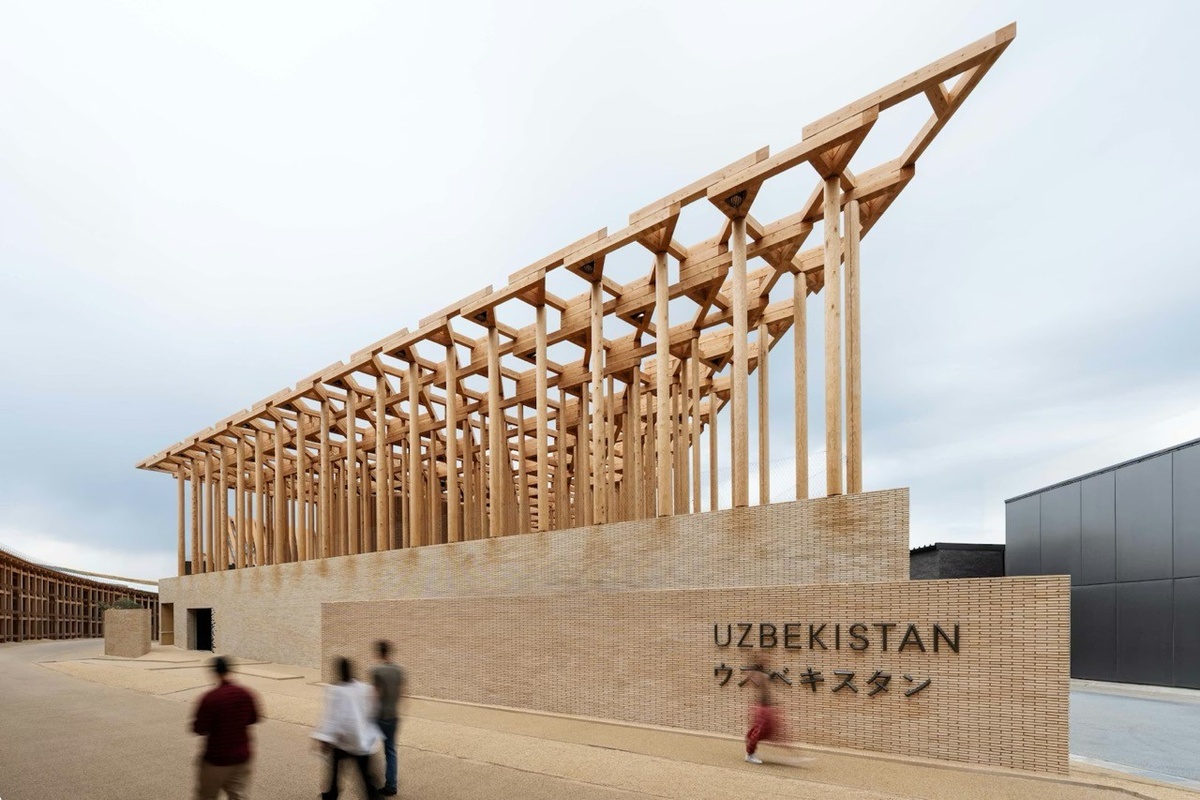 Modern wooden structure of Uzbekistan Pavilion with people walking in front.