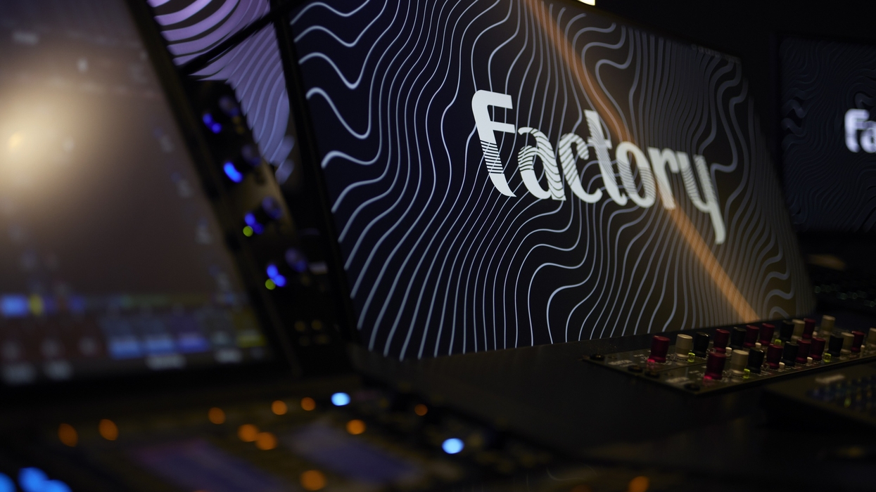 Monitors with "Factory" text and wavy lines in a dark, high-tech studio.