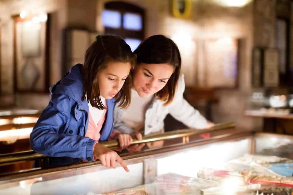 mother and daughter look at exhibit together in museum
