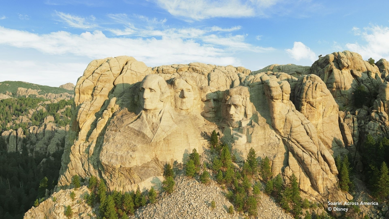 Mount Rushmore with clear skies and surrounding forest, part of Disney's Soarin' Across America