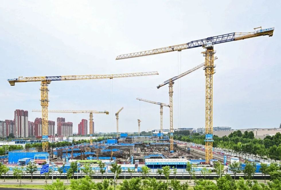 Multiple cranes at a the Beijing Haichang Ocean Park construction site, with buildings in the background.