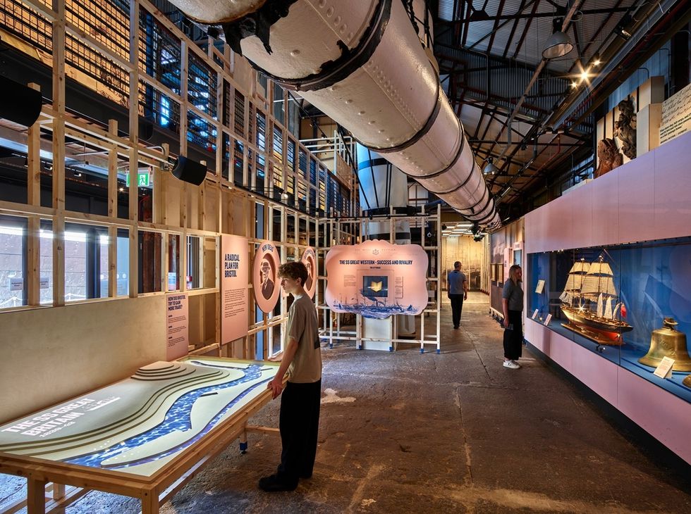 Museum exhibit at the SS Great Britain Experience, with interactive displays, ship model, and informative panels. Visitors observing.