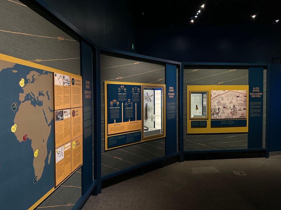 Museum exhibit on early human migration with maps and archaeological displays.