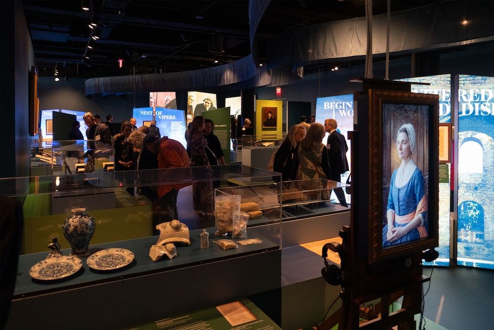 Museum exhibit, The First Salute, with visitors viewing art and historical artifacts.