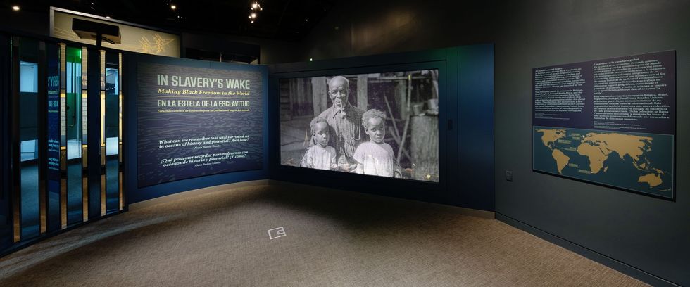Museum exhibit titled "In Slavery's Wake" with historical images and world map.