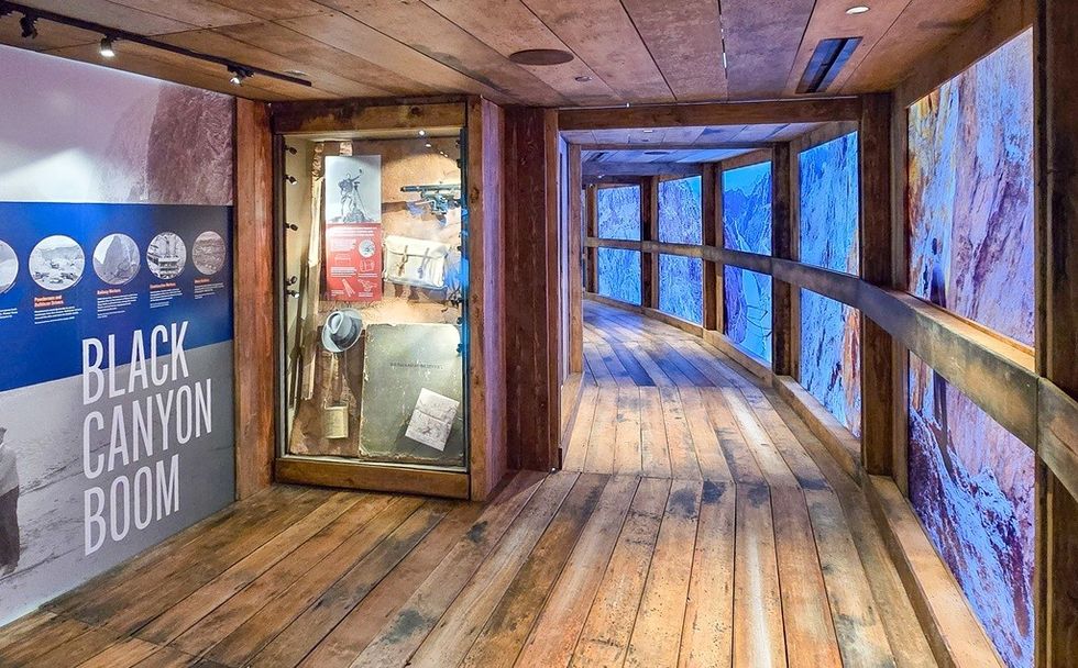 Museum exhibit with "Black Canyon Boom" sign, wooden floor, and large display windows.
