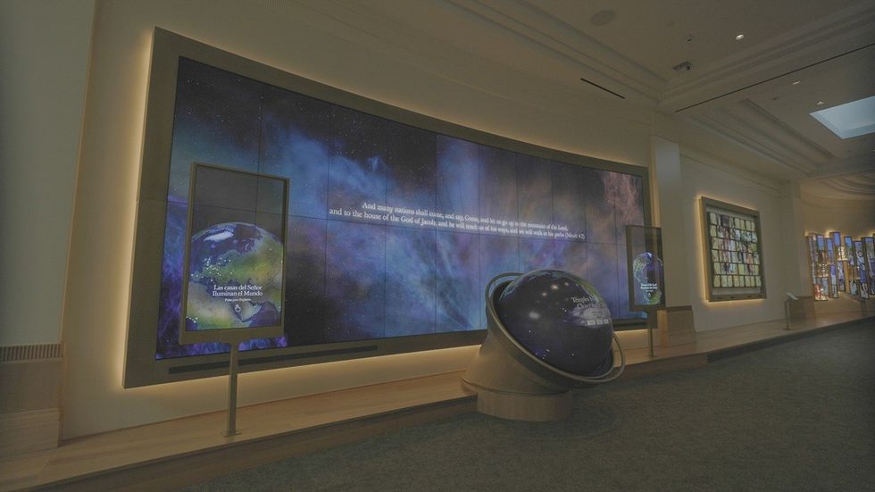 Museum exhibit with large digital screens and a globe, featuring space imagery and text.