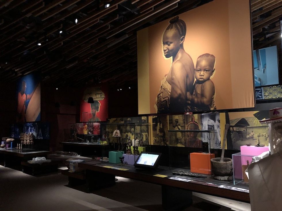 Museum exhibit with large portrait of a woman carrying a child on her back.